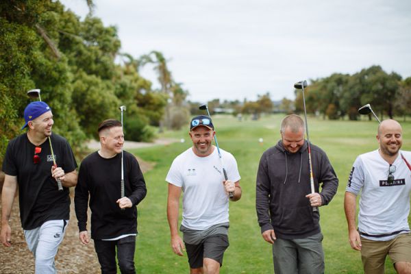 Groomsmen walking the fairway with clubs on the wedding morning