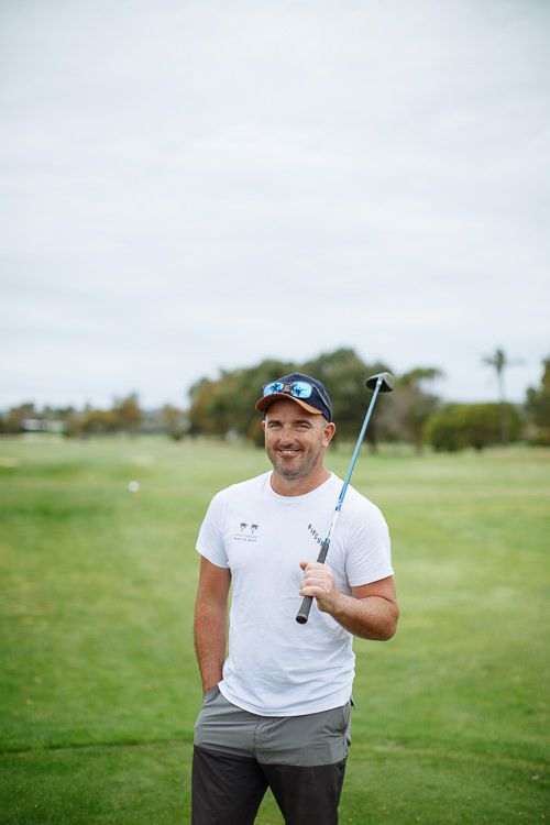 Groom smiling on the golf course before getting dressed for the ceremony