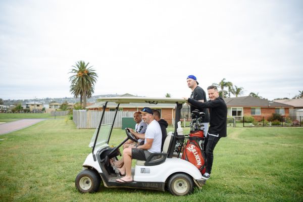 Groomsmen riding golf carts between holes on the wedding morning