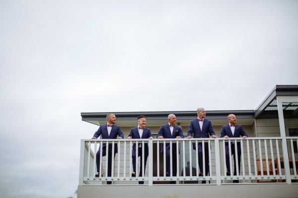 Groomsmen lined along the balcony rail in navy suits