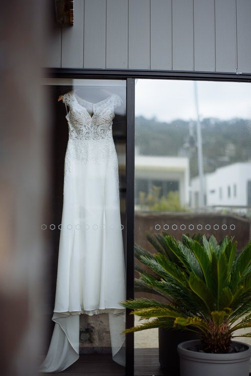 Caitlin's lace wedding gown hanging in the window light