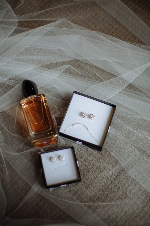 Bride's perfume, earrings and jewellery styled on tulle
