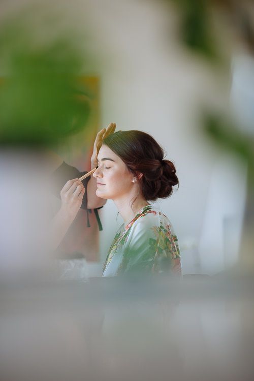 Bride having her makeup applied in her floral robe