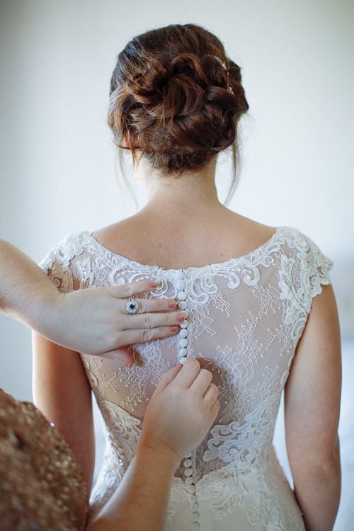 The lace illusion back of Caitlin's gown being fastened