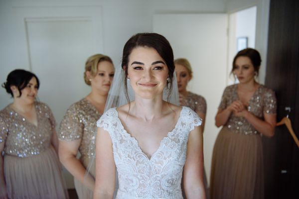 Bridesmaids in sequinned blush gowns surrounding the bride