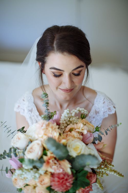 Bride looking down at her peach bouquet – natural bridal portrait