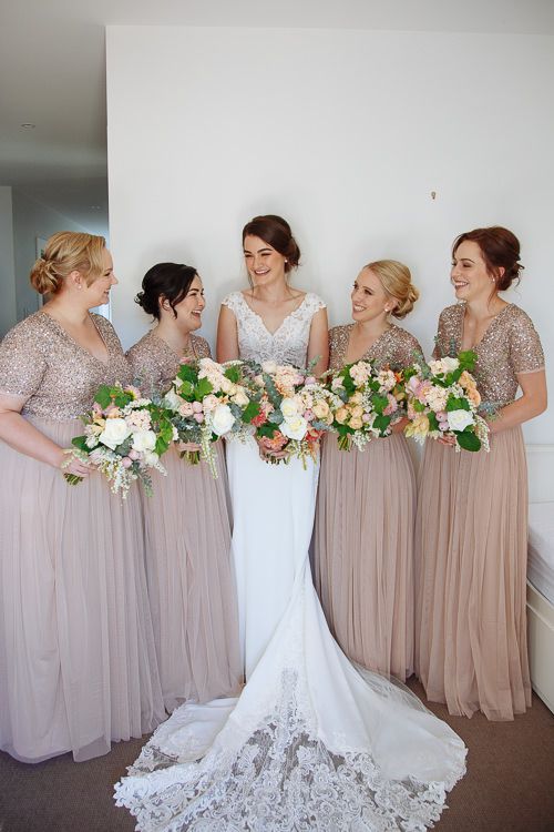 Bride and bridesmaids lined up with peach bouquets in blush gowns