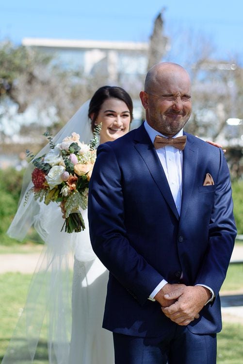 Bride beaming beside the groom during their coastal first look