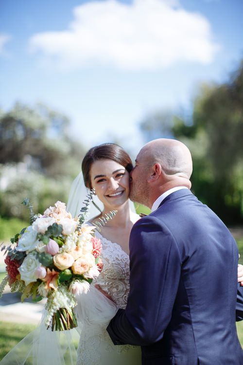 Groom kissing the bride's cheek after the first look
