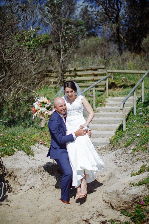 Couple seated on the timber beach steps with the bouquet