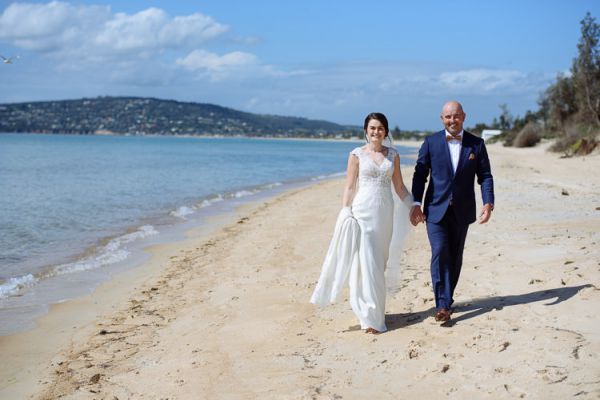 Caitlin and Brad walking the sand near Dromana, hills across the bay