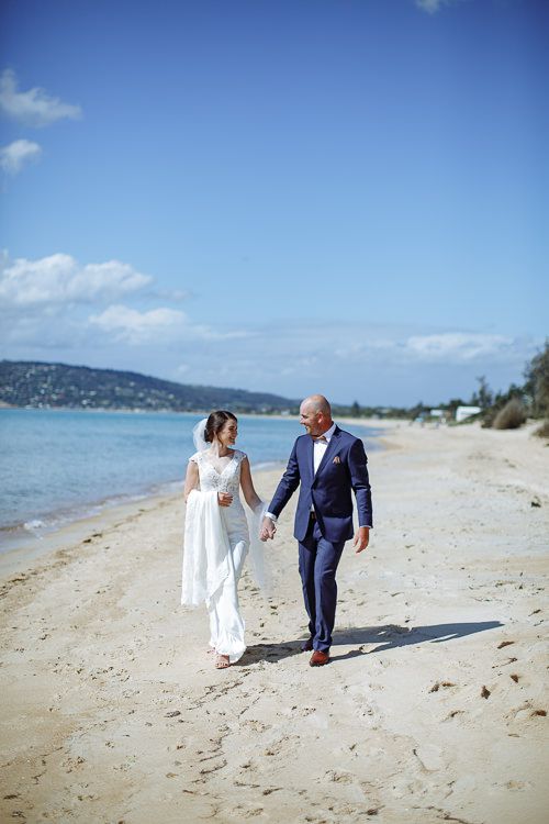 Bride and groom strolling the shoreline hand in hand