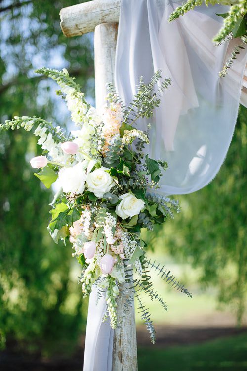 White and blush florals draped on the timber ceremony arch