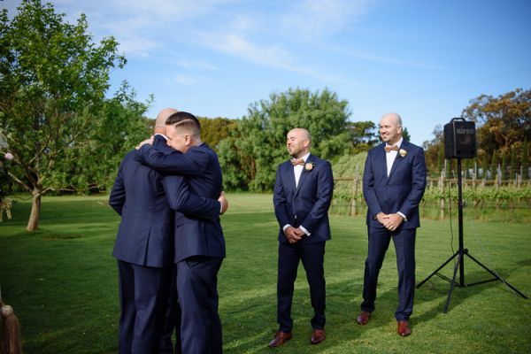 Groom embracing his groomsmen before taking his place at the arch
