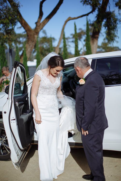 Bride stepping out of the wedding car with her father