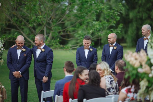 Groomsmen sharing a joke as guests take their seats