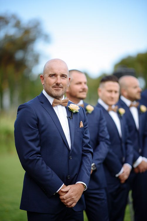 Groom watching the aisle with his groomsmen at his shoulder