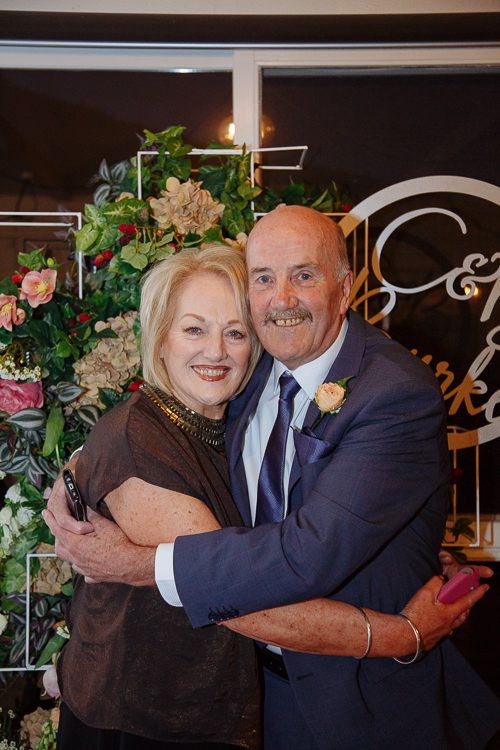 Grandparents embracing by the floral 'C & B' sign