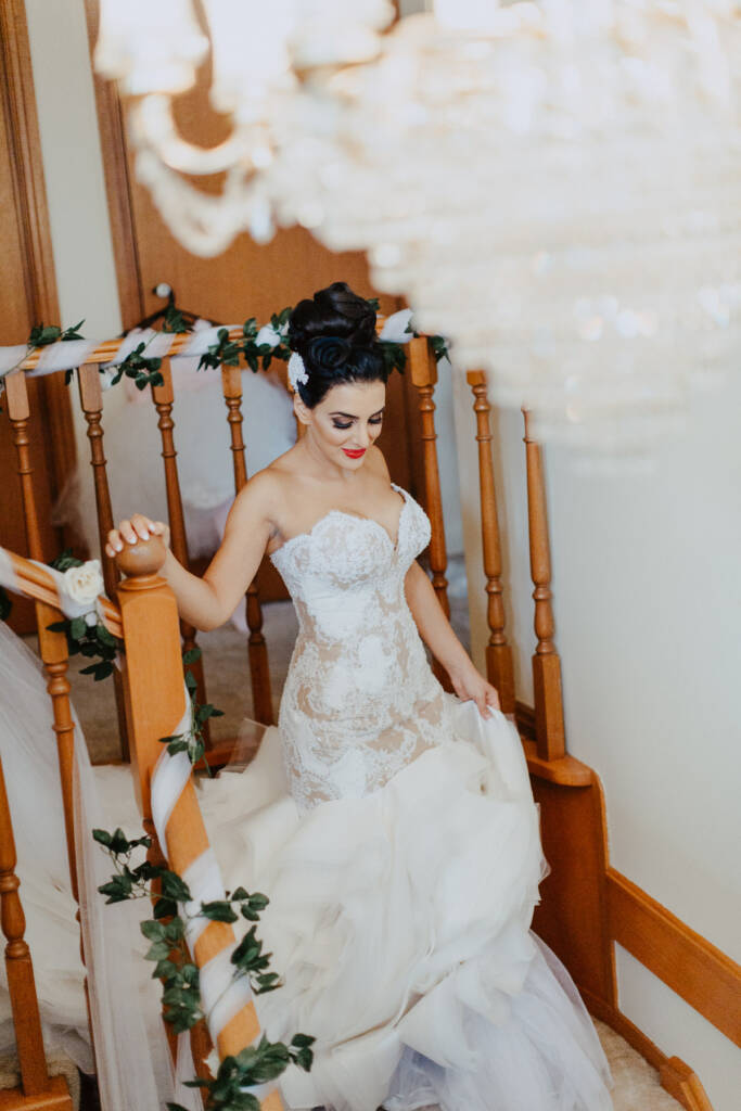 Danielle lifts her ruffled skirt as she walks down the timber stairs