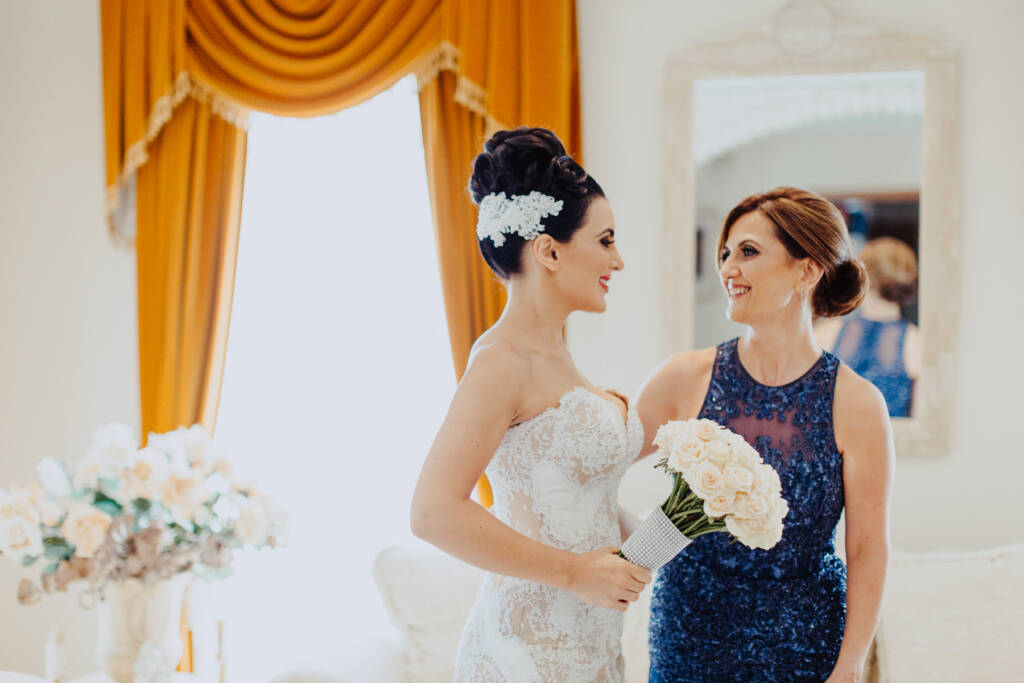 Danielle smiles with a woman in a navy dress during bridal preparation