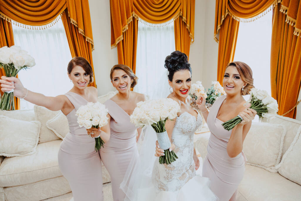 Danielle and her bridesmaids raise their bouquets for a wedding-party portrait