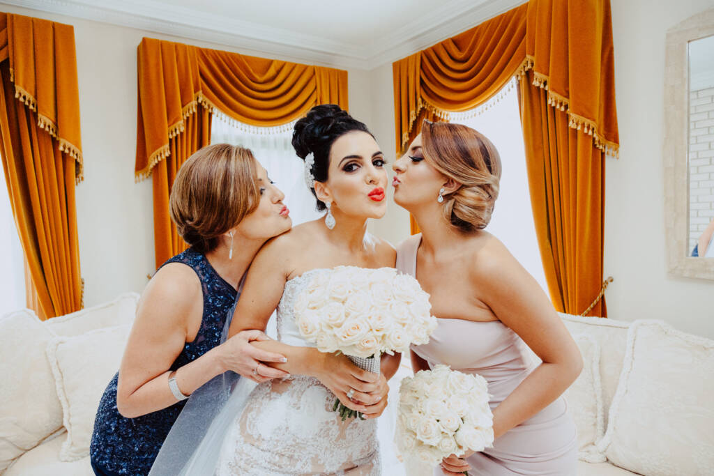 Two women kiss Danielle's cheeks as she poses between them