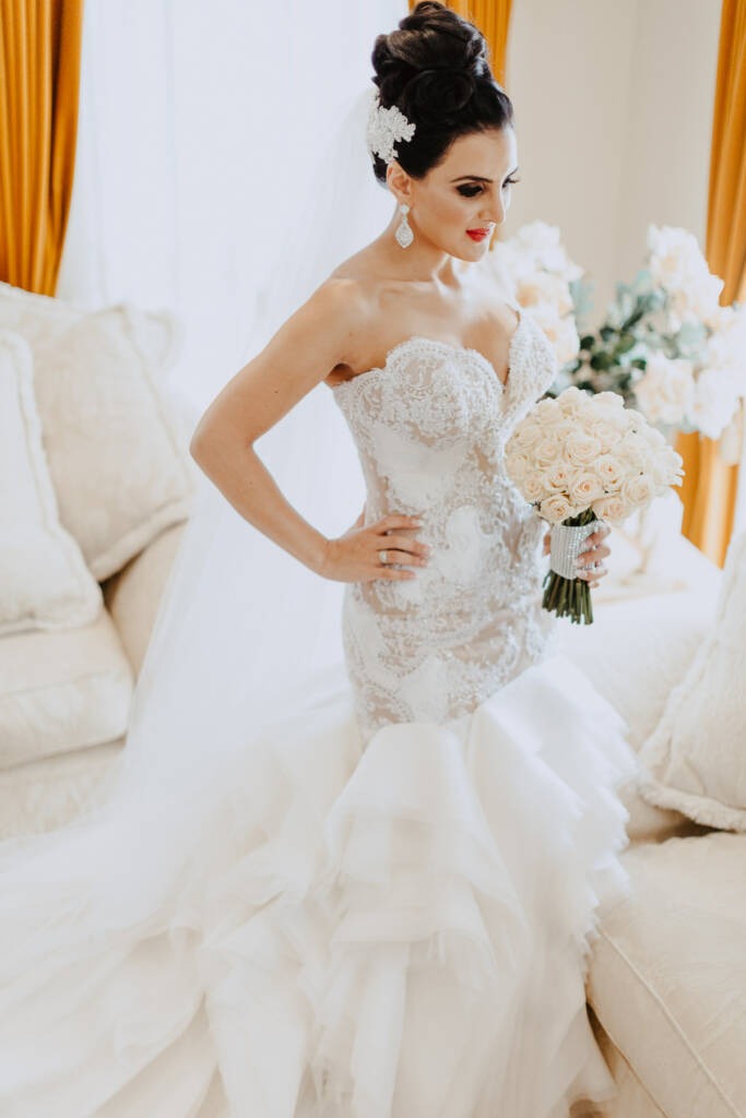 Danielle poses with her bouquet in a fitted lace gown with a ruffled skirt