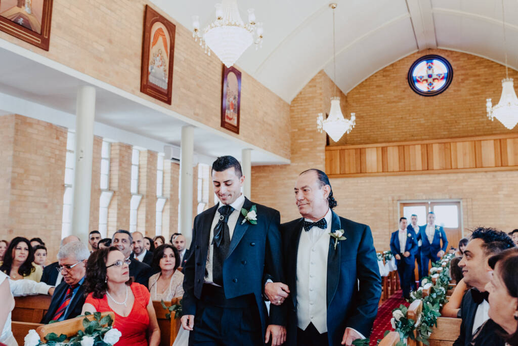 Michael walks down the aisle with an older man at St Aphrem Syrian Orthodox Church