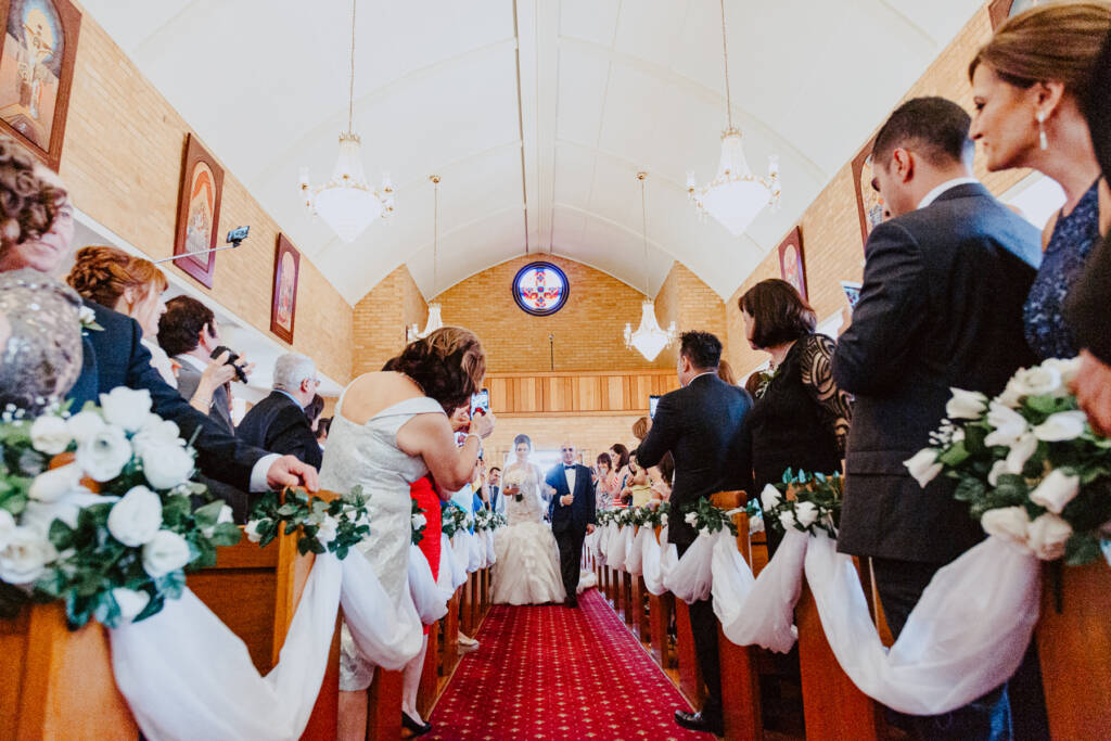 Guests photograph Danielle walking down the aisle at St Aphrem in Preston