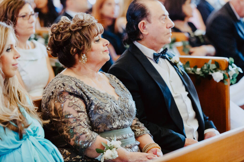 Guests watch the ceremony beside flower-decorated pews at St Aphrem