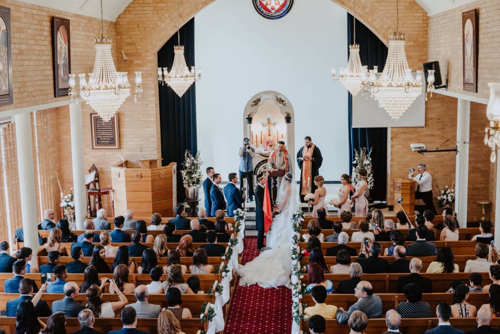 Clergy stand with Danielle and Michael during their church wedding at St Aphrem