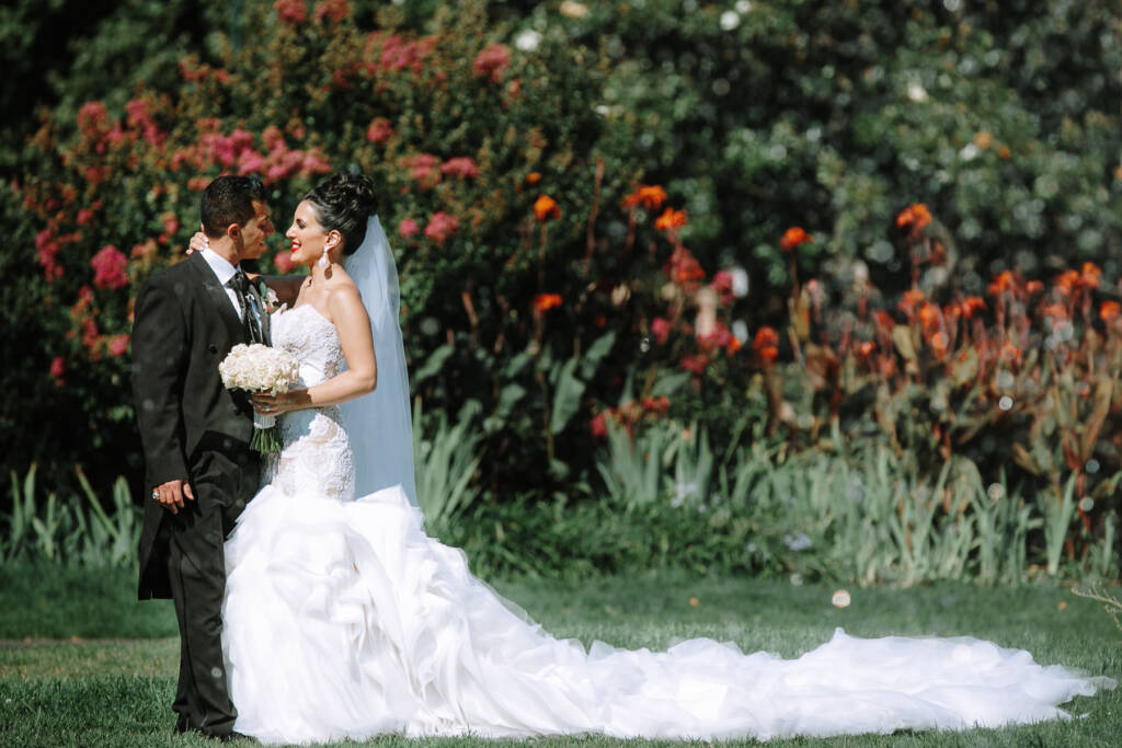 Danielle and Michael embrace beside flower beds for garden wedding portraits at Carlton Gardens
