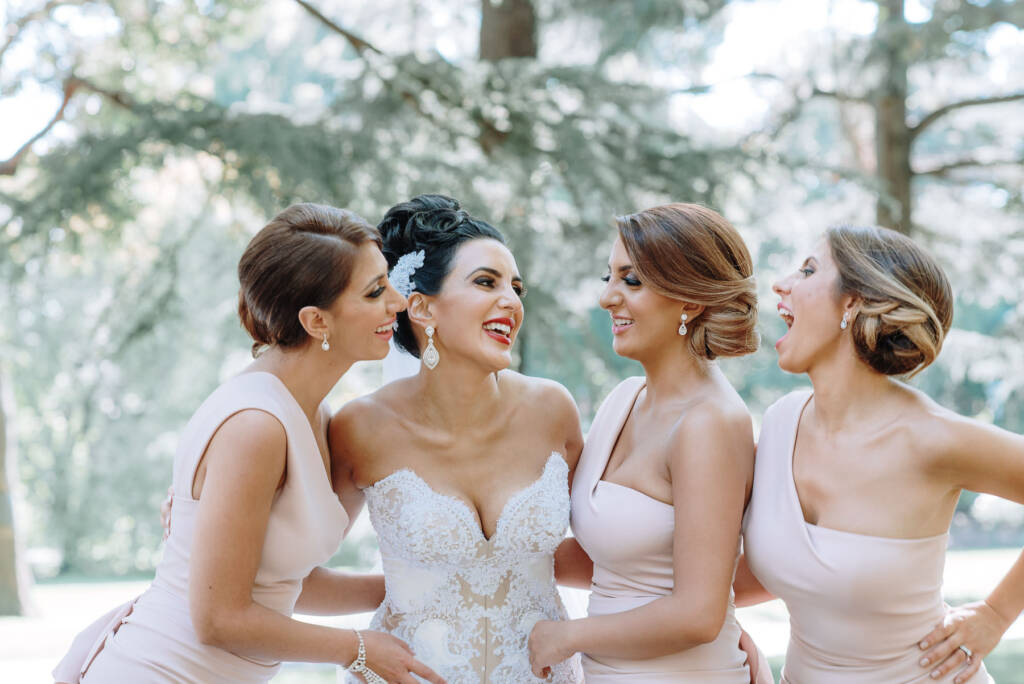 Danielle laughs with her three bridesmaids during garden wedding portraits at Carlton Gardens