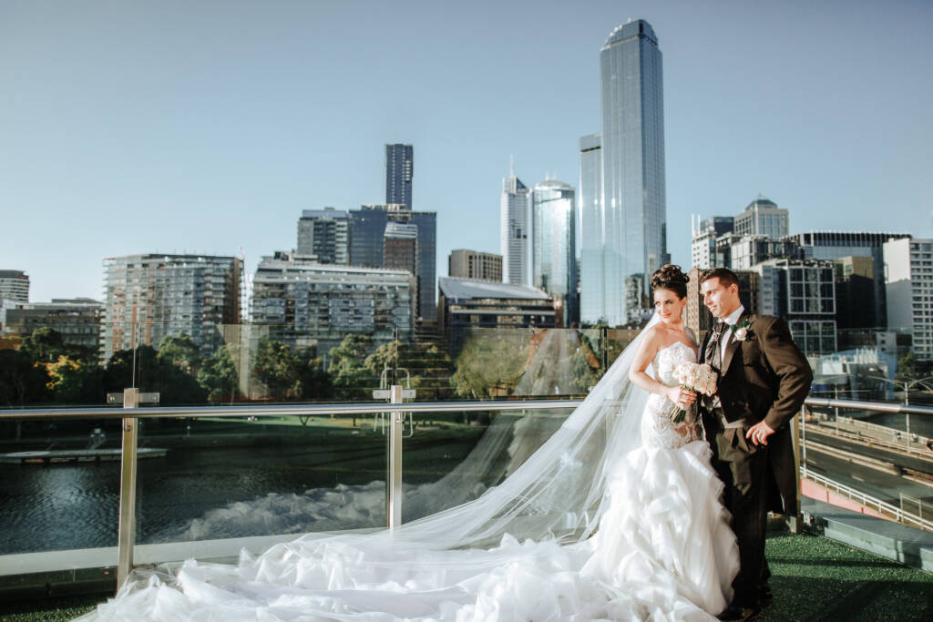 Danielle and Michael pose on the Crown Towers rooftop with the Melbourne CBD skyline behind