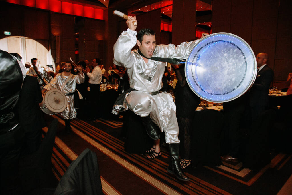 A zaffe drummer raises his drumstick among reception guests at Crown Palladium