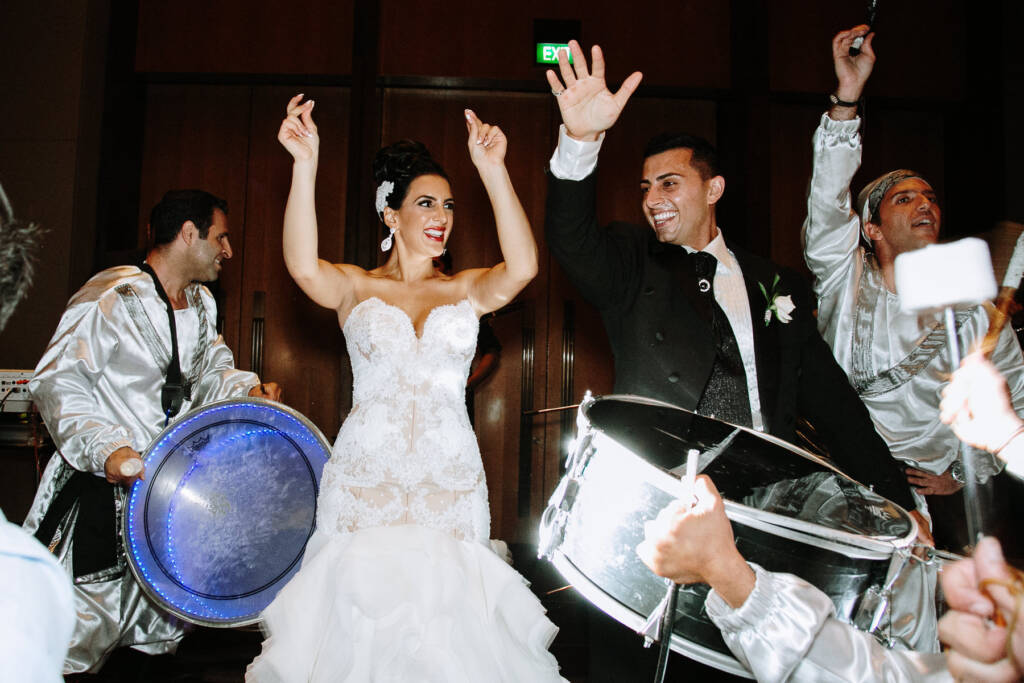 Danielle and Michael raise their hands among drummers during their Lebanese wedding reception