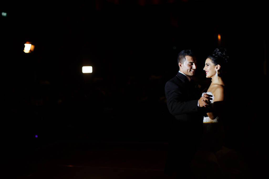 Danielle and Michael smile during their spotlit first dance at Crown Palladium