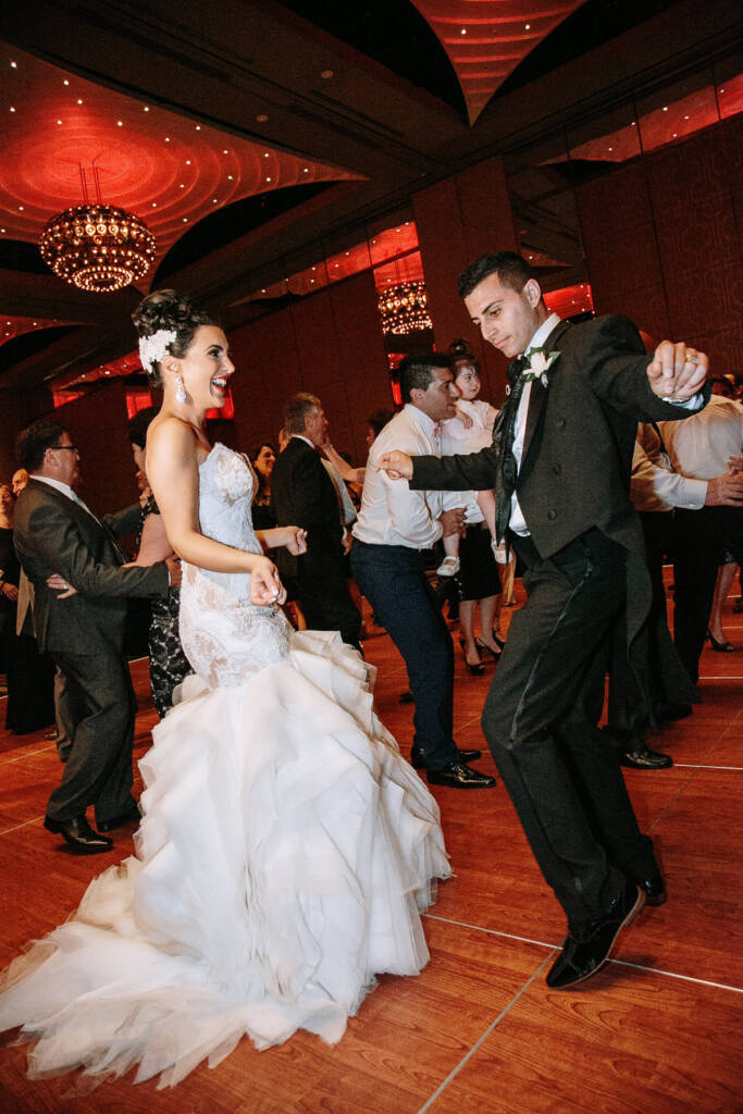 Danielle and Michael dance among guests beneath red-lit chandeliers at Palladium at Crown