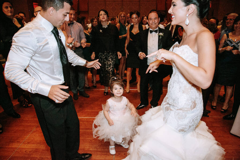 A young girl stands between Danielle and Michael as they dance with guests