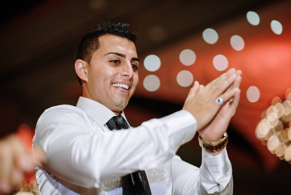 Michael smiles and claps with blurred ballroom lights behind him at Palladium at Crown