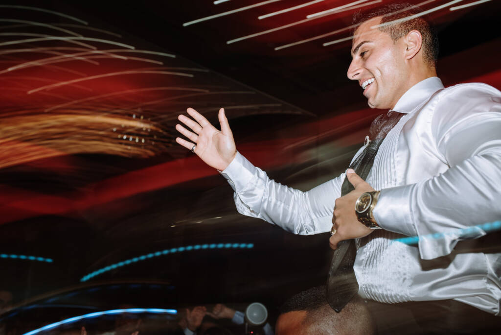 Michael smiles on a guest's shoulders amid ballroom light trails at Palladium at Crown