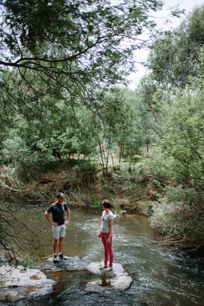 Camilla and Jason face each other from separate stream rocks at Flowerdale Estate.