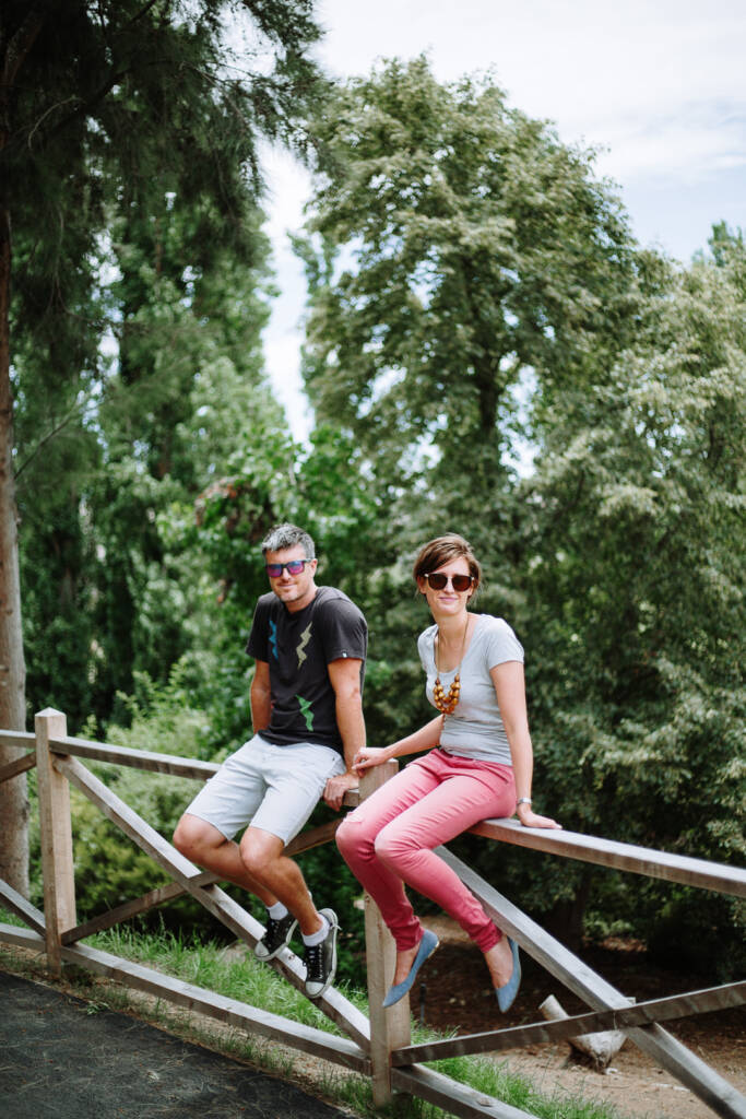 Camilla and Jason sit holding hands on a timber fence at Flowerdale during their engagement shoot.