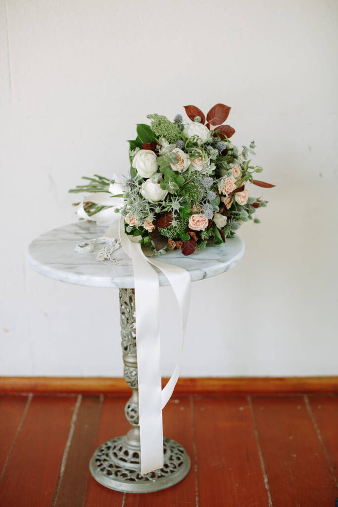 Camilla's bridal bouquet and accessories rest on a round table at Flowerdale Estate.