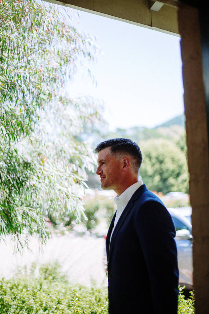 Jason stands in profile beneath the Flowerdale verandah, looking towards the grounds.