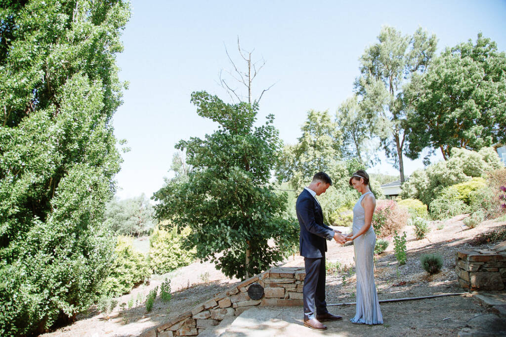 Camilla and Jason hold hands on stone steps in the Flowerdale Estate garden.
