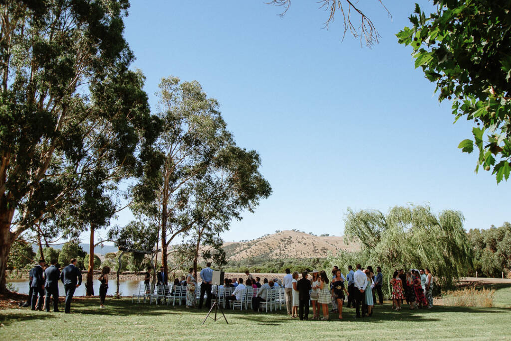 Guests gather beside the lake for Camilla and Jason's waterside ceremony at Flowerdale.