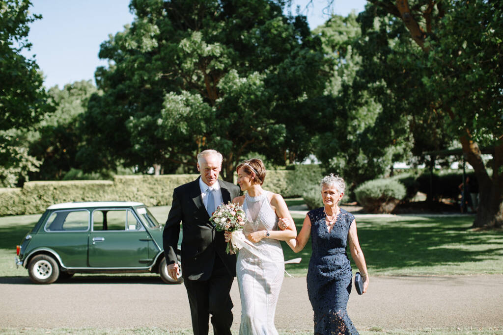 Camilla walks towards the ceremony with two companions at Flowerdale Estate.