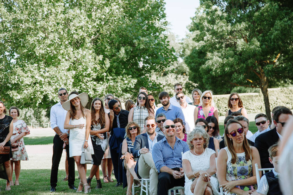 Wedding guests watch the outdoor ceremony among the trees at Flowerdale.