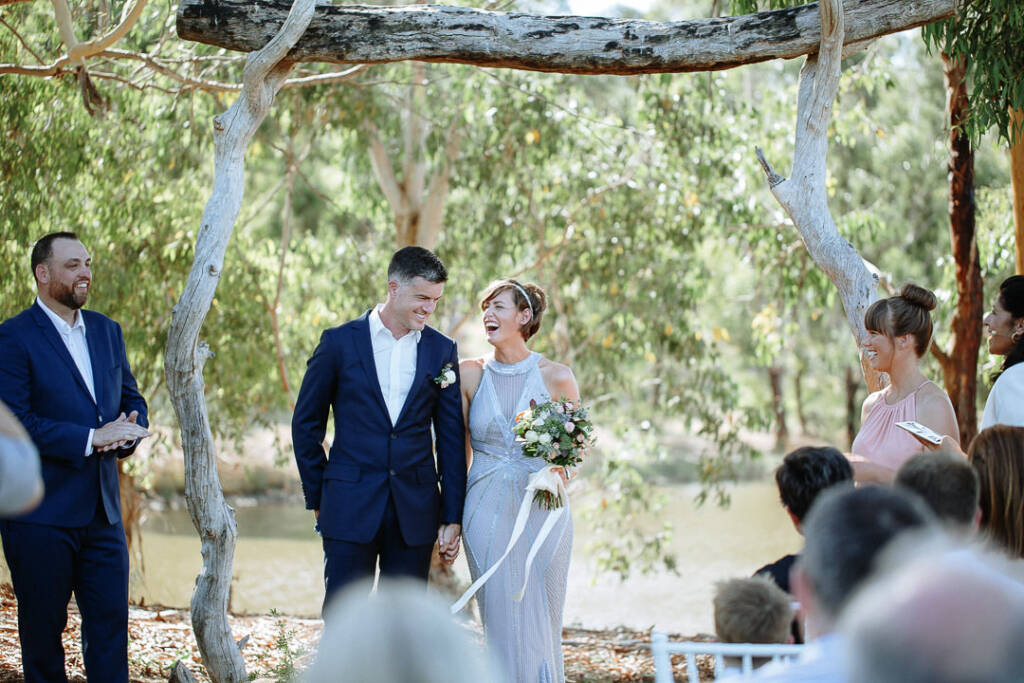 Camilla and Jason laugh together beneath the Flowerdale Estate ceremony arbour.